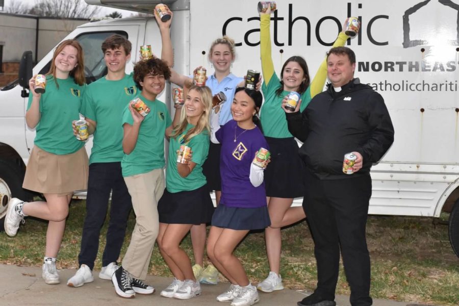 Senior council members  smile with Fr. Andrew in front of the catholic charities collection bus